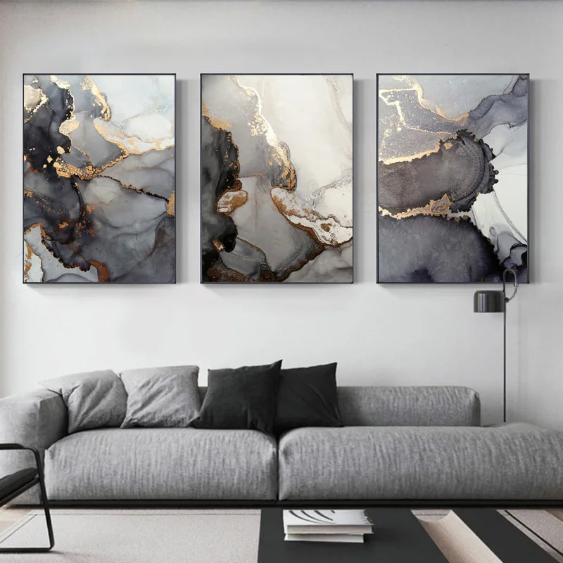 Three abstract wall art pieces above a gray sofa in a living room.