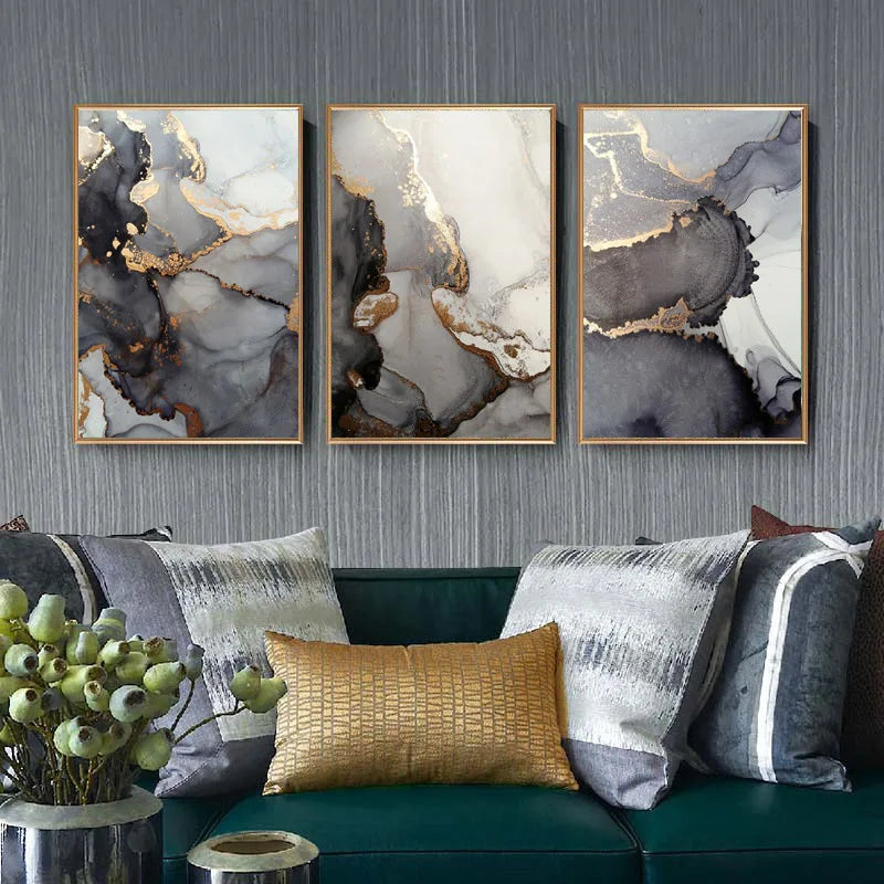 Three abstract art pieces on a wall above a sofa with decorative pillows.