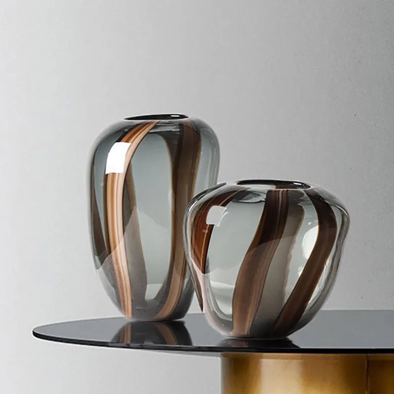 Two glass vases with striped design on a black surface against a gray background