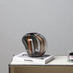 Decorative glass vase on a Chanel book with a gray background
