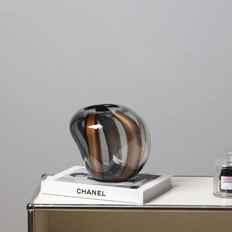 Decorative glass vase on a Chanel book with a gray background