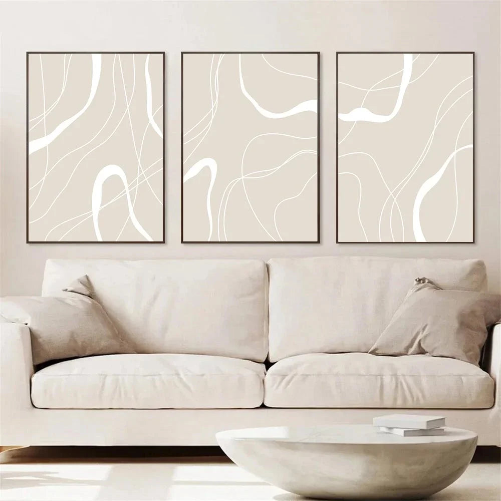 Three abstract wall art pieces above a beige sofa in a living room.