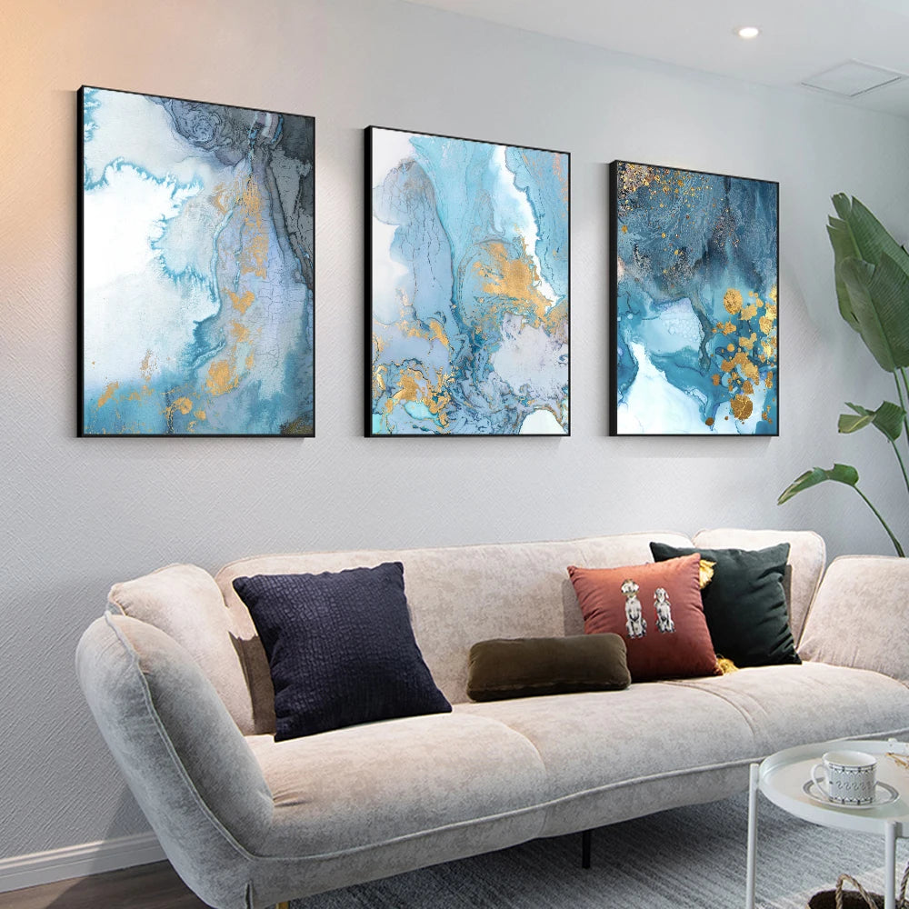 Three abstract art pieces on a wall above a sofa with decorative pillows.