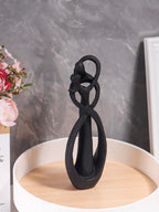 Black decorative object on a wooden stand with a marble wall background