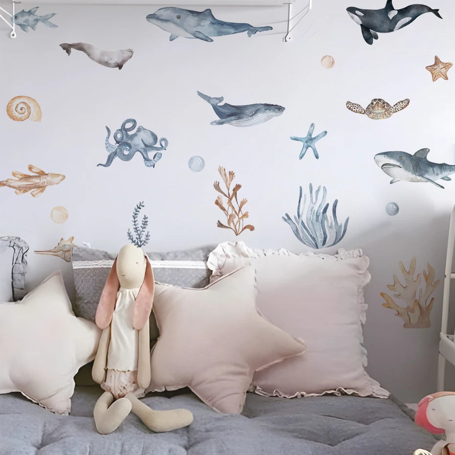 Children's room with ocean-themed wall decals, plush toys, and decorative pillows.
