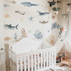 Nursery room with white crib, ocean-themed wall decals, and decorative elements.