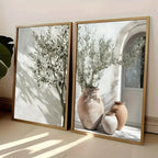 Two framed pictures of vases with plants on a light-colored floor.