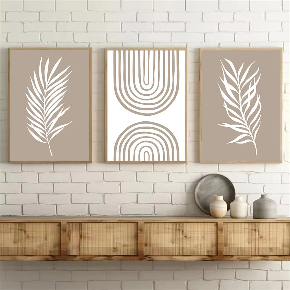 Three framed prints with leaf and arch designs on a white brick wall above a wooden console table.
