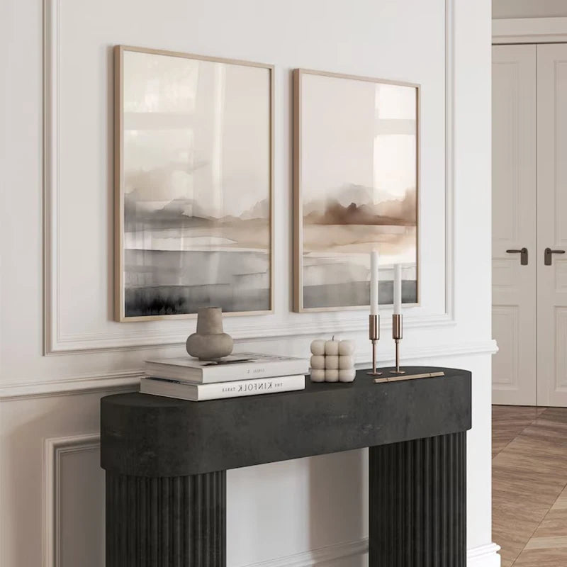 Two abstract paintings on a wall above a black fireplace mantle with decorative items.
