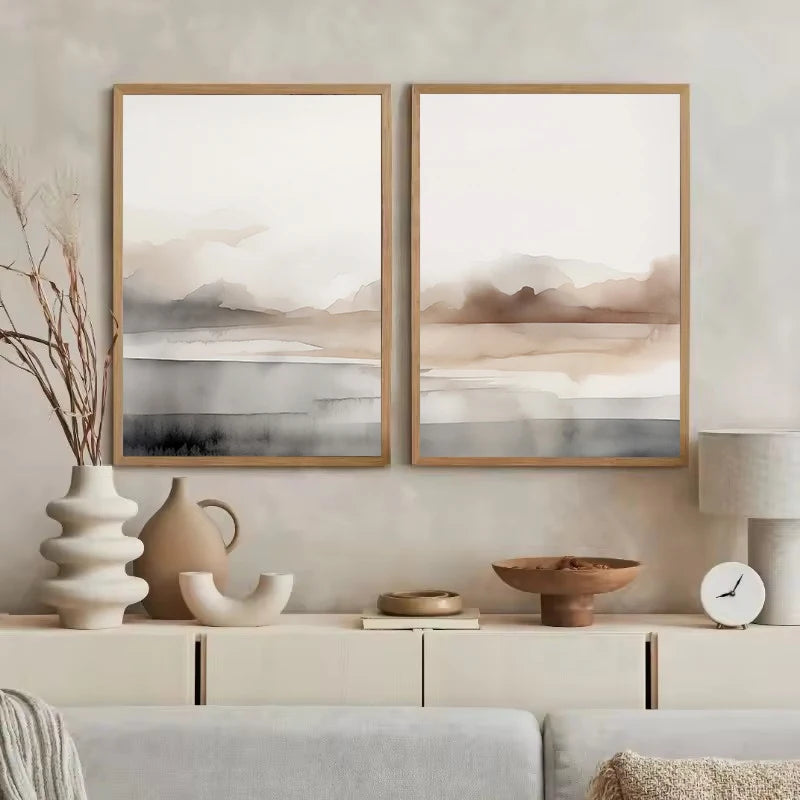Two framed abstract landscape paintings on a wall above a cabinet with decorative items.