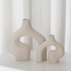 Two beige ceramic vases with abstract designs on a white background