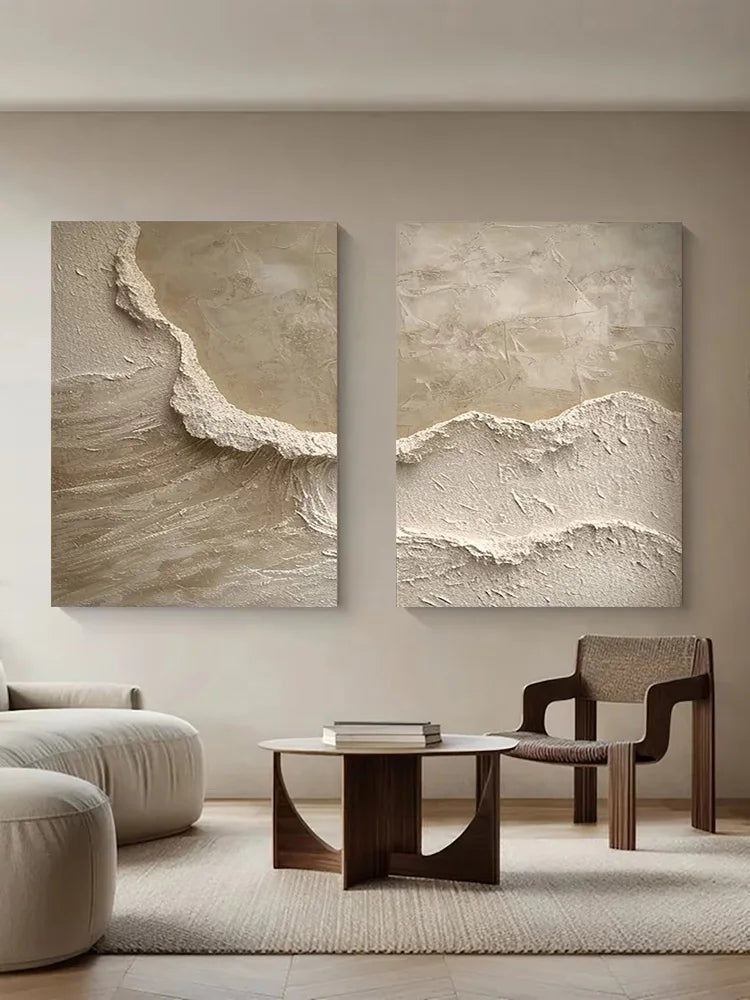 Two abstract wall art pieces on a beige wall above a modern living room setup.