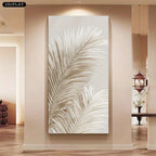 A large vertical canvas wall art piece featuring a stylized cream and white palm leaf design, displayed on a beige wall in a modern hallway interior.