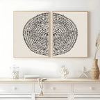 Two black circular abstract artworks on a white wall above a white console table.