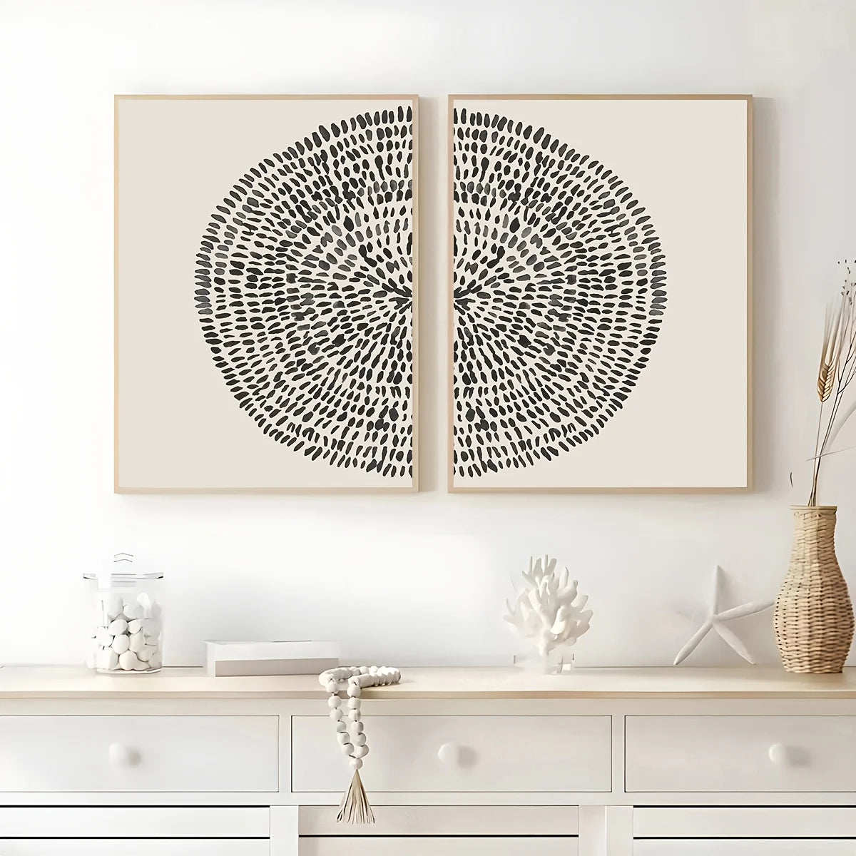 Two black circular abstract artworks on a white wall above a white console table.