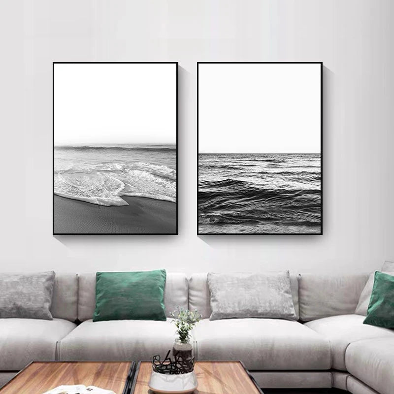 Two framed black and white ocean artworks on a wall above a sofa.