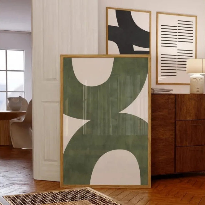 Abstract art pieces on a wall in a room with wooden flooring and furniture.