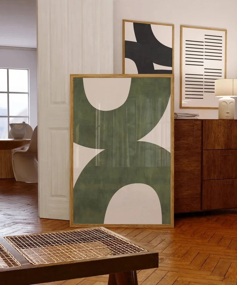 Abstract art pieces on a wall in a room with wooden flooring and furniture.