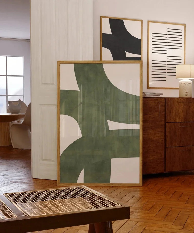 Abstract art pieces on a wall in a room with wooden flooring and furniture.