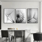 Three black and white framed artworks of dandelion seeds on a wall above a dining table.