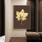 Decorative wall art with gold leaf design on a brown background in a modern interior setting.