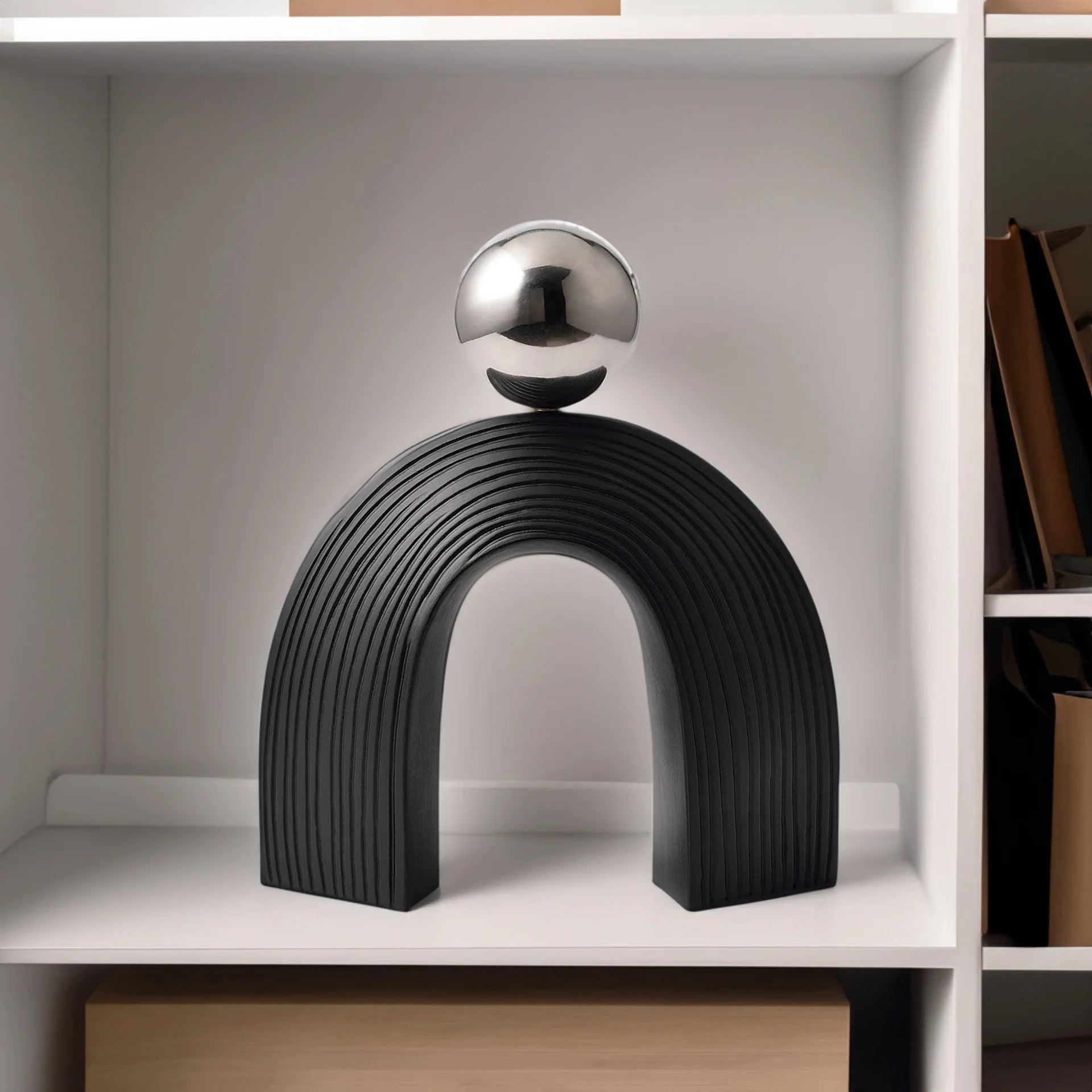 Decorative sculpture with a black arch and silver sphere on a shelf.
