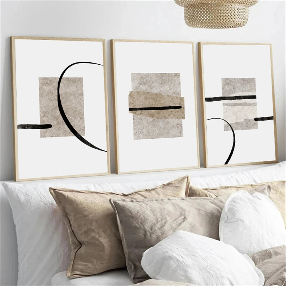 Three abstract art prints on a wall above a sofa with pillows.
