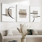 Three abstract art pieces on a wall above a sofa with decorative elements.