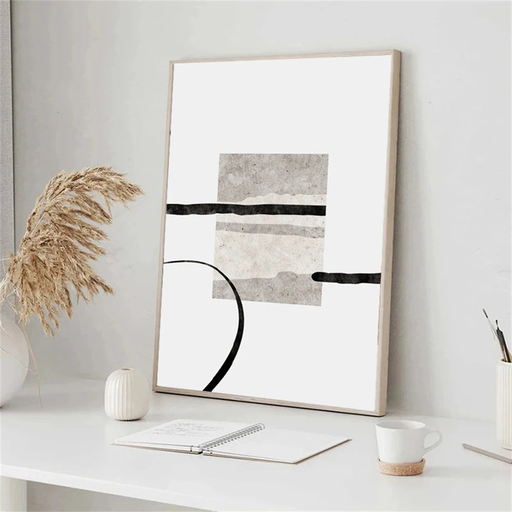 Framed abstract art on a white wall above a desk with decor items.
