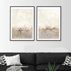 Two framed abstract artworks on a wall above a dark sofa with cushions.