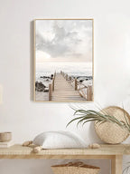 Framed beach scene print on a wall above a wooden bench with decorative items.
