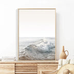 Framed artwork of a wave on a wall above a wooden cabinet.