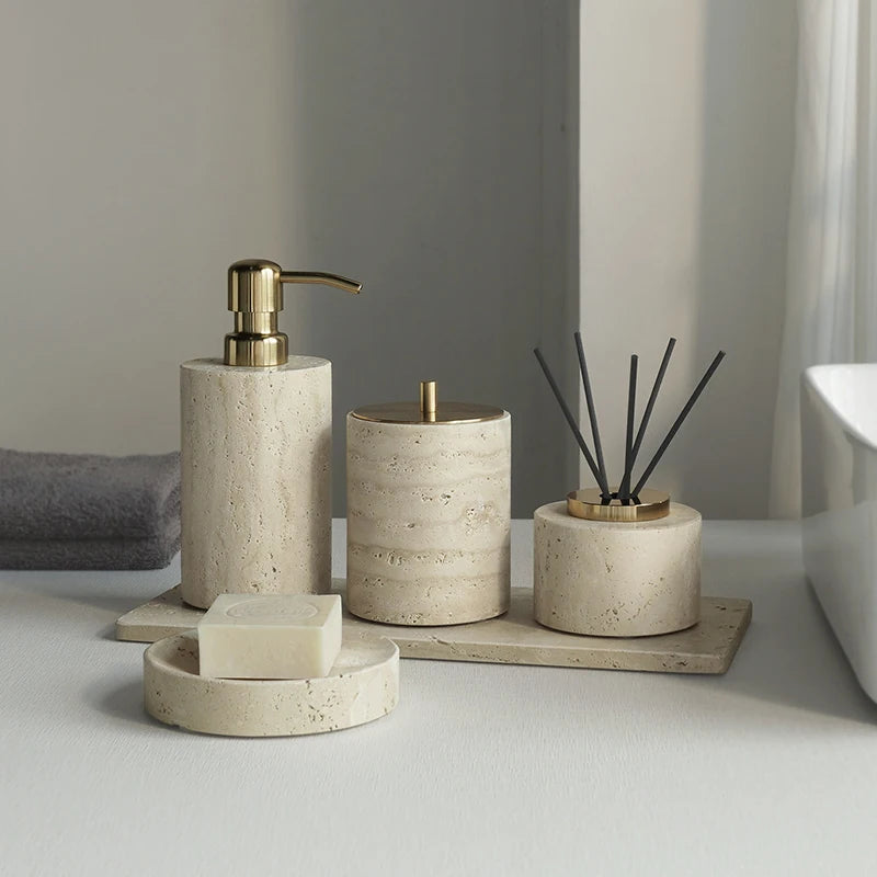 Bathroom accessories including a soap dispenser, candle, and diffuser on a neutral background.