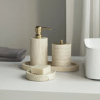 Bathroom accessories including a soap dispenser, candle, and soap on a white surface.