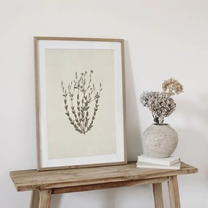 Framed botanical print on a wooden table with a vase of flowers.