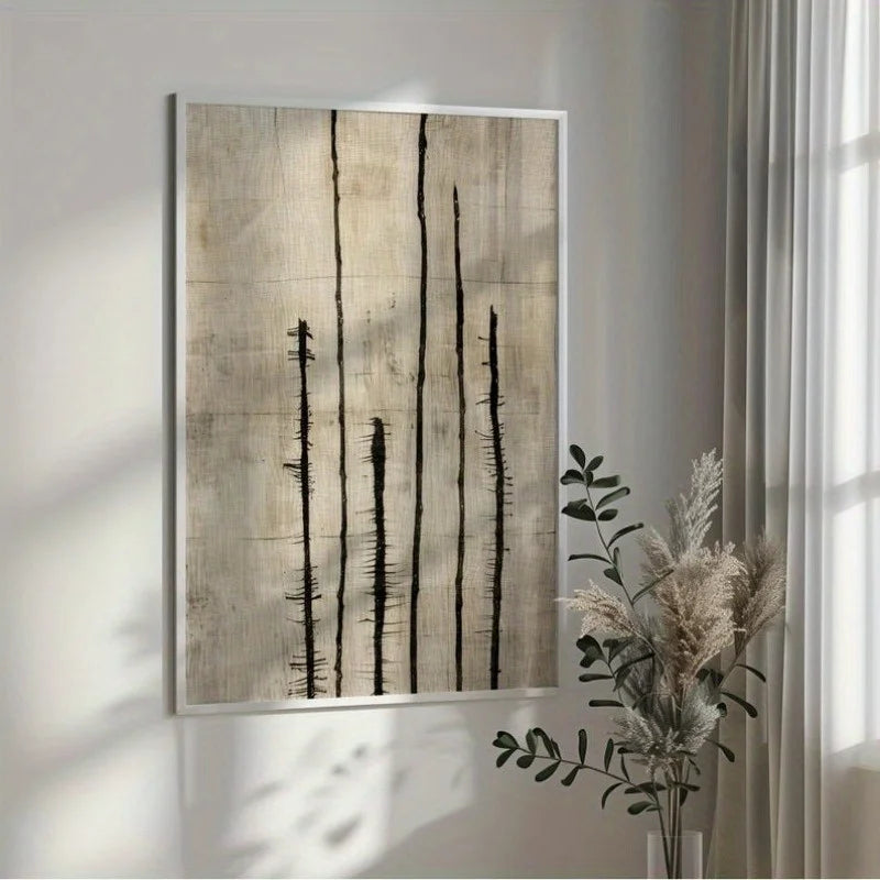 An abstract wall art print with vertical black brushstrokes on a textured beige background, hanging on a light gray wall in a styled interior next to a vase with dried grasses.