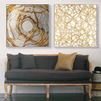 Two abstract art pieces on a wall above a gray sofa with decorative pillows.