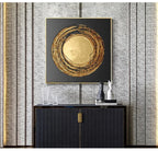 Decorative wall art with gold circular design on a textured wall above a black cabinet.
