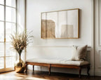 Wooden bench with a cushion in a room with a large window and abstract art on the wall.