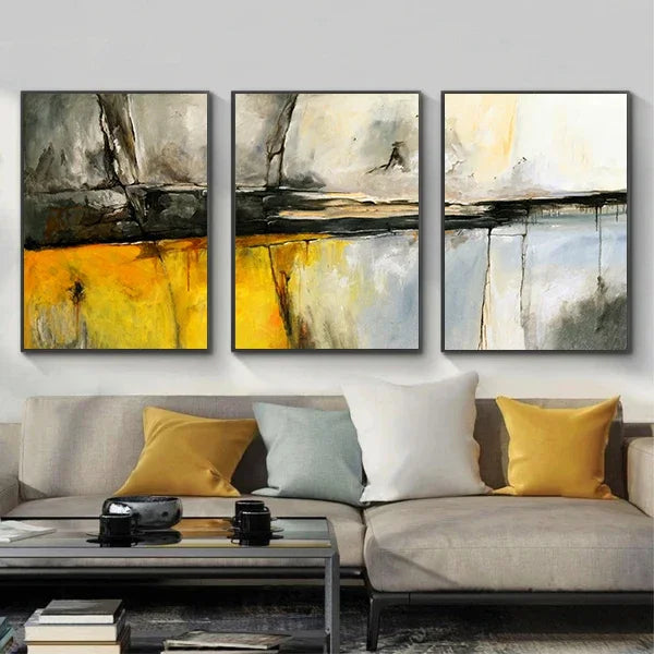 Three abstract paintings above a sofa with colorful cushions in a living room setting.