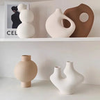 Collection of modern ceramic vases on a white shelf with a minimal background