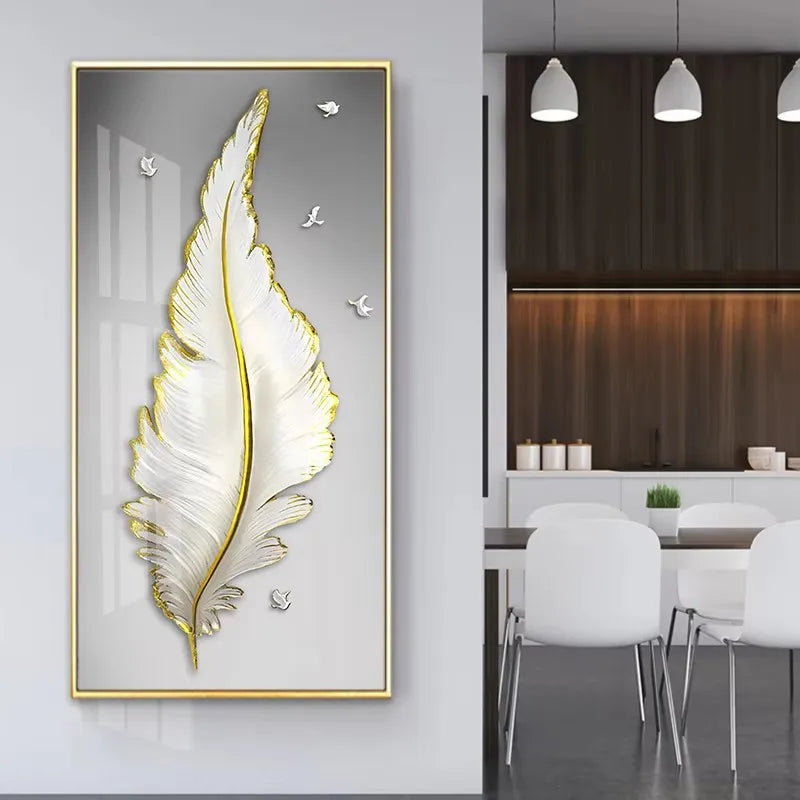 Decorative wall art of a feather with gold frame on a white wall, with a modern dining area in the background.