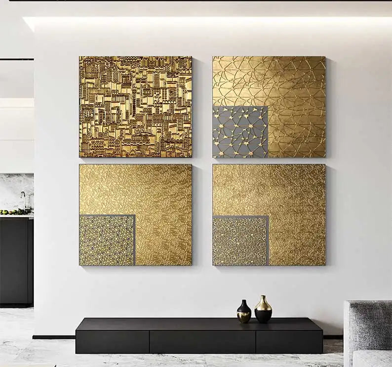 Set of four gold and gray abstract wall art pieces on a white wall.