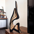 Black and beige shoe sculpture on a wooden surface with a blurred background