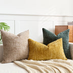 Three textured pillows in beige, yellow, and green on a bed with a white headboard.
