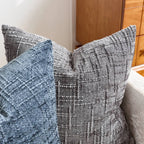 Textured throw pillows on a sofa with a wooden cabinet in the background