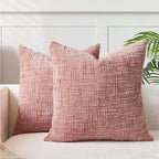 Two pink textured pillows on a white couch with a neutral background