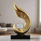 Gold decorative sculpture with a glass sphere on a black base in a living room setting