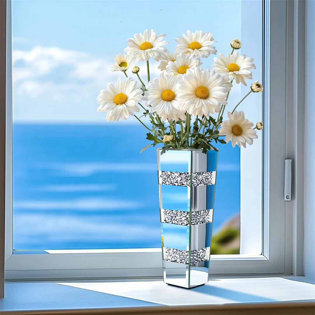 Decorative vase with white flowers on a windowsill with a view of the ocean.