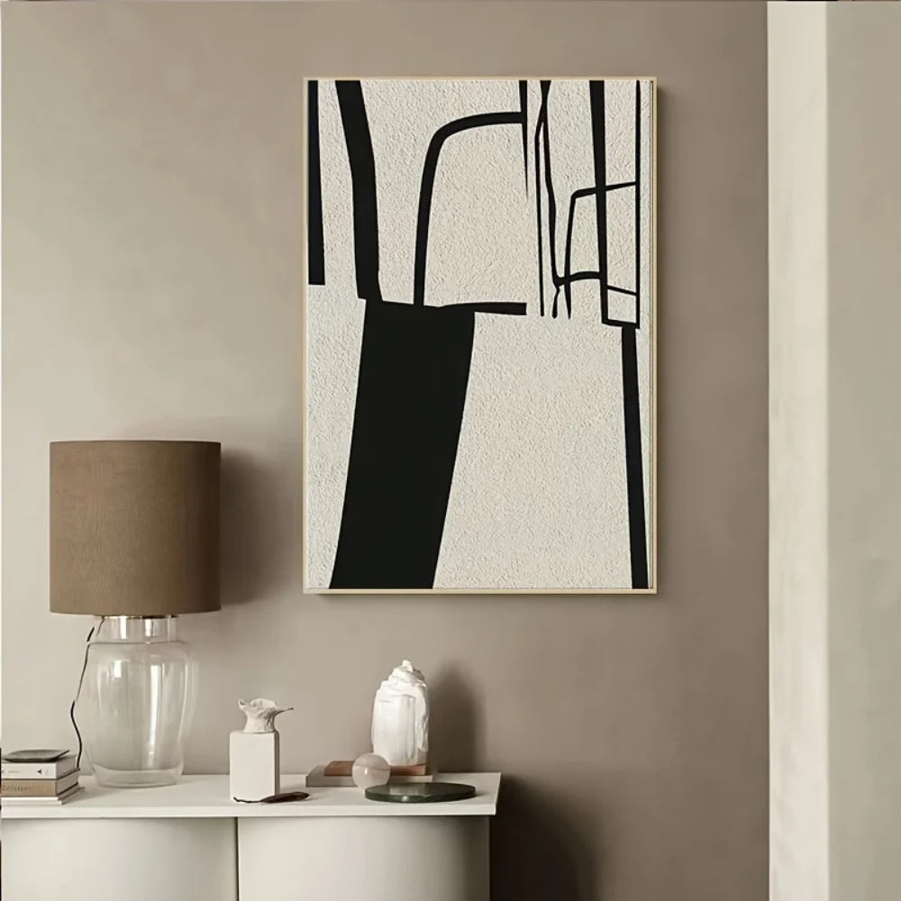 Abstract black and white painting on a beige wall above a white console table with decor items.